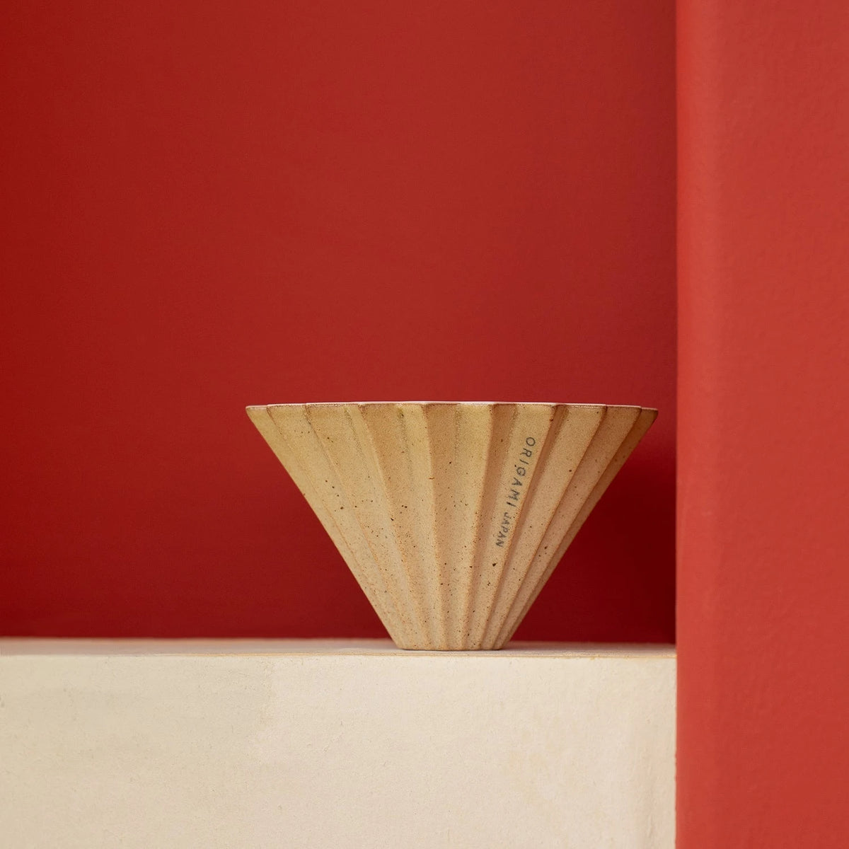 Origami Dripper S Sabi Limited Edition – auf hellem Sockel vor roter Wand – Barista Delight